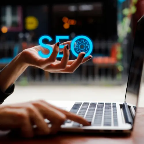 Close-up of hands typing on a laptop with an SEO graphic overlay, representing search engine optimization services in Rock Hill and Fort Mill.