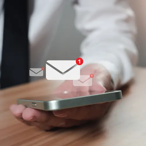 Person in business attire holding a smartphone with an email icon overlay, representing email marketing and automation services for Rock Hill and Fort Mill businesses