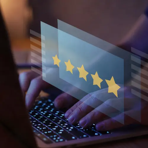 Hands typing on a laptop with floating five-star icons, representing online review and reputation management for Rock Hill and Fort Mill businesses.