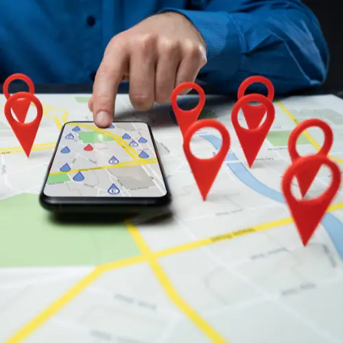 Hand pointing to a smartphone map with location pins, representing local SEO and business listings optimization in Rock Hill and Fort Mill.